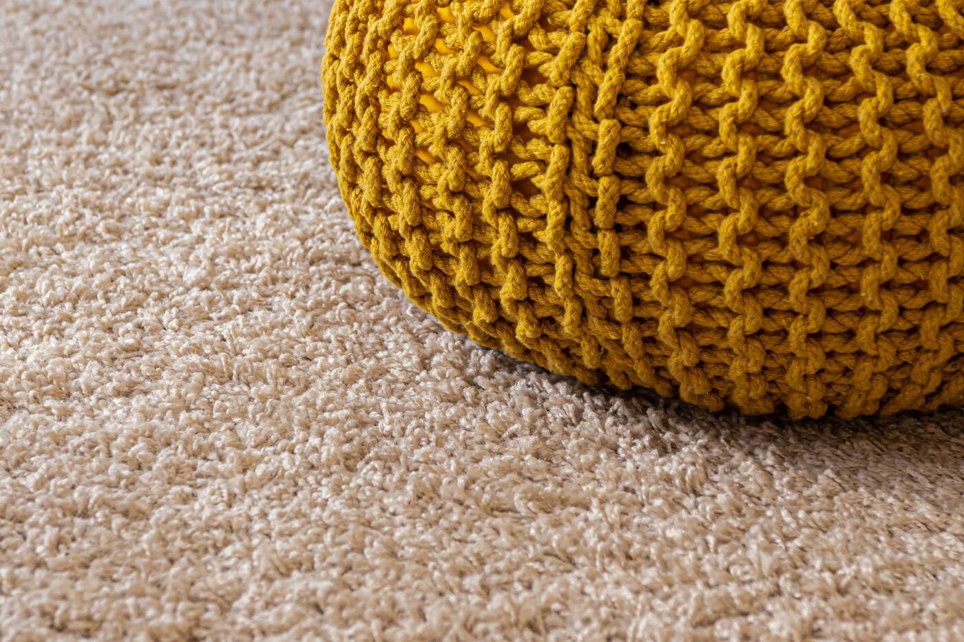 Close view of carpet fibers beside a knitted pouf.