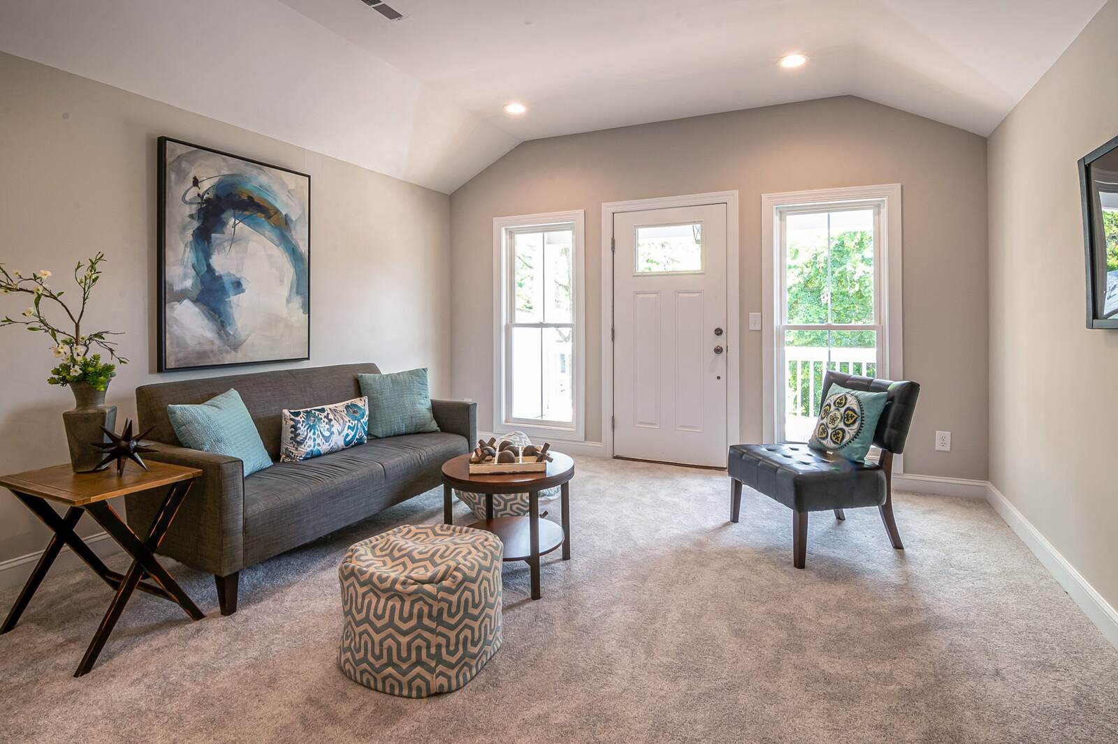 A living room with wall-to-wall carpet, a sofa, and chairs.