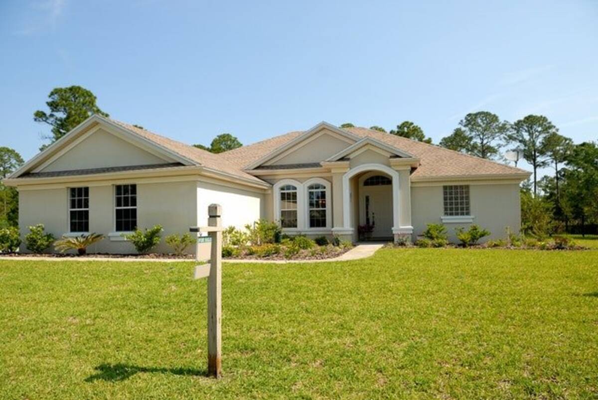 A one-story house with a for-sale sign in the front yard.