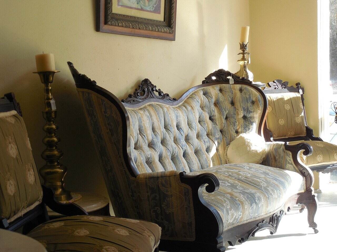 A tufted sofa with carved wood trim in a sunlit room.